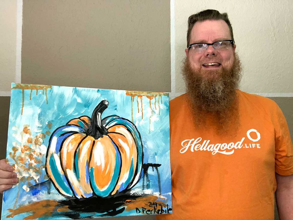 Dale Berkebile of Hellagood Life holding an abstract pumpkin painting for the Fort Worth Paint & Sip event.