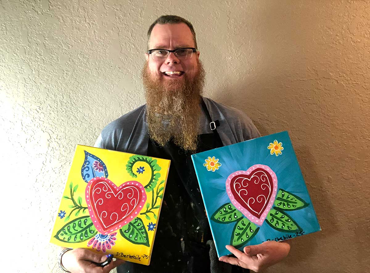Dale holding the 2 paintings for the 2025 Valentines Day Paint & Sip